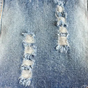 Primo piano del tessuto denim strappato su gilet per animali con fili bianchi sfilacciati