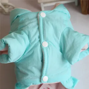 Close-up detail of a mint green padded pet winter coat showing white snap buttons