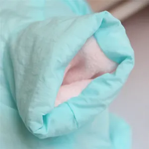 Close-up of pet winter coat detail showing soft pink plush lining and blue fabric