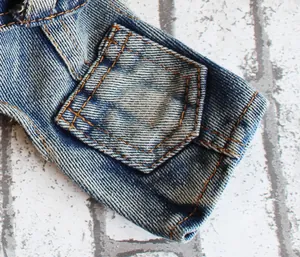 Detailopname van de hoogwaardige stiksels en zak op de blauwe denim jumpsuit voor honden.