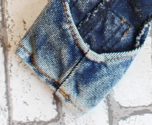 Detaillierte opname van denim huisdier jumpsuit met focus op de stiksels en de textuur