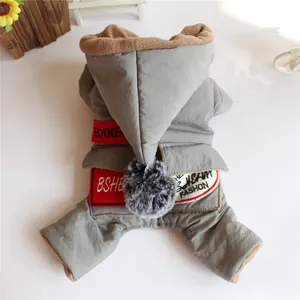 Detailansicht eines grauen Winter-Hundeoveralls mit Kapuze, Bommel und modischen Aufnähern.