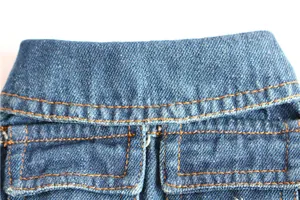 Detailed close-up view of blue denim pet vest featuring orange stitching and front pockets.
