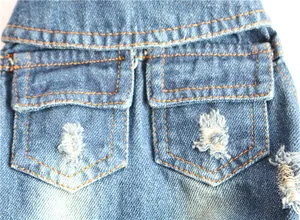 Close-up of dog denim vest featuring ripped distressed holes and double pocket detail.