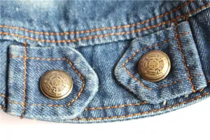 Detail view of durable denim pet vest with decorative embossed bronze-tone metal buttons