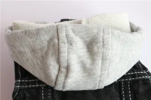 Dettaglio ravvicinato del morbido cappuccio grigio fissato a un gilet di jeans nero