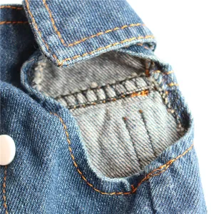 Close-up detail shot of the armhole and orange stitching on a blue pet denim vest