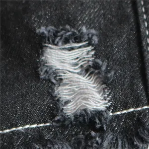 Primo piano macro del tessuto denim strappato invecchiato su un gilet per cani domestici