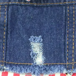 Detailopname van distressed denim hondenkleding met gescheurde details en stiksels