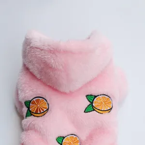 Detail van de zachte pluche textuur en geborduurde sinaasappelpatronen op de roze hondenhoodie