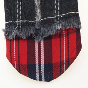 Close-up detail showing the red plaid patchwork and frayed denim edges of a dog vest