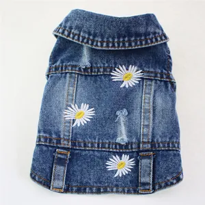 Close-up detail of a blue denim pet vest featuring daisy embroidery and ripped holes.