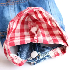 Detailed close-up of dog denim vest featuring red plaid lining and snap buttons