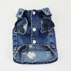 Detailed macro view of embroidered daisy on blue denim pet vest with white snap buttons.