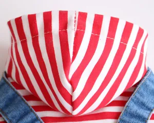 Close-up detail of a soft red and white striped pet hoodie featuring blue denim straps