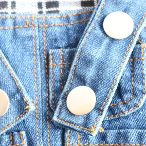 Macro detail view of denim pet overalls showing white buttons and orange stitching.