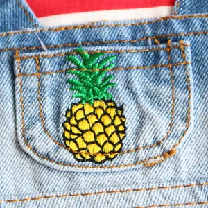Close-up of pineapple embroidery on light blue denim pocket of a pet dress.