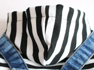 Vue détaillée d'un sweat à capuche rayé noir et blanc pour animal avec bretelles en jean.