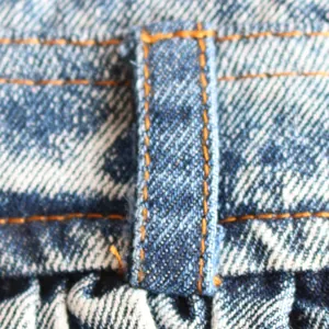 Makroansicht der stabilen orangefarbenen Nähte an der blauen Jeansrock-Schlaufe