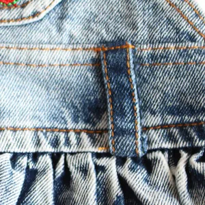 Nahaufnahme eines gewaschenen Denim-Haustierkleids mit orangefarbenen Nähten und Falten