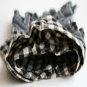 Detailansicht eines Hundekleides mit schwarz-weißem Karomuster und weißem Druckknopf