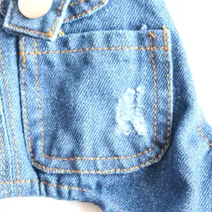 Close-up macro detail of blue denim pet jacket showing a distressed pocket and stitching