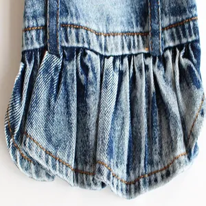 Detailansicht der gewaschenen blauen Denim-Textur und des gerüschten Saums eines Hundekleides