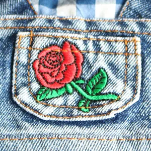Detailed macro shot of red rose flower embroidery on blue denim pet skirt pocket