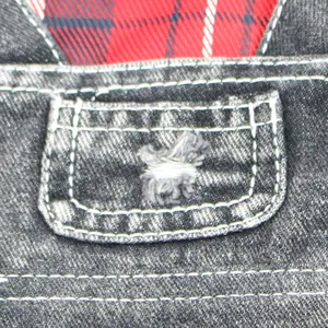 Macro view of pet denim jumpsuit pocket detail with red plaid fabric lining detail