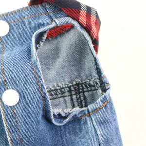 Close-up detail of dog denim vest with plaid lining and distressed sleeve opening.