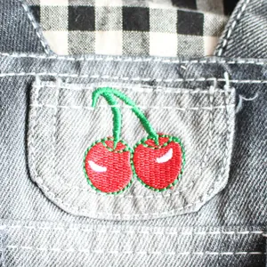 Detailansicht der roten Kirschstickerei auf einer grauen Denim-Tasche für Haustiere