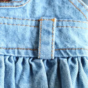 Primer plano macro de un vestido vaquero azul claro para mascotas con trabillas y pliegues
