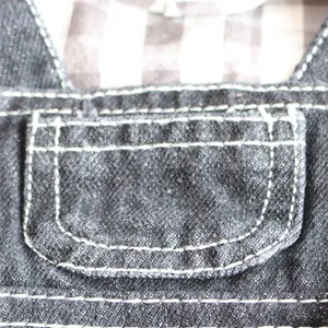 Close-up of pet denim overall featuring decorative pocket and white contrast stitching