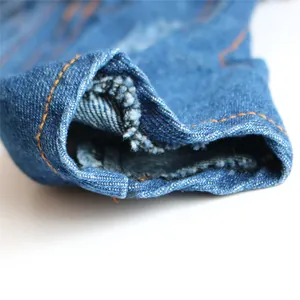Macro detail of blue denim pet clothing showing orange stitching and fabric texture