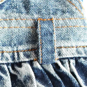 Close-up view of a blue denim pet skirt featuring durable orange stitching details