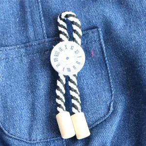 Detail von dekorativem Uhrenanhänger mit schwarz-weißem Seil für Haustierkleidung.