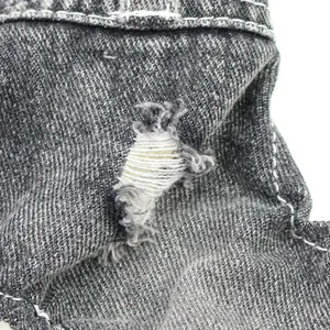 Close-up macro view of the distressed ripped detail on grey denim dog jumpsuit fabric