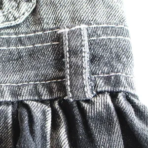 Macro close-up showing the denim fabric texture and white stitching of a pet dress.