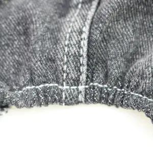 Close-up macro detail of white stitching on durable dark grey pet denim jumpsuit fabric