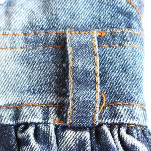 Gros plan sur le tissu denim durable et les coutures contrastées orange des vêtements pour animaux.