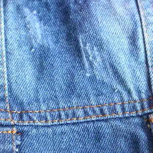 Close-up of blue denim fabric with yellow double-needle stitching on a dog vest