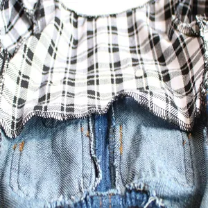 Detailed view showing the plaid fabric lining and denim stitching of pet clothes.
