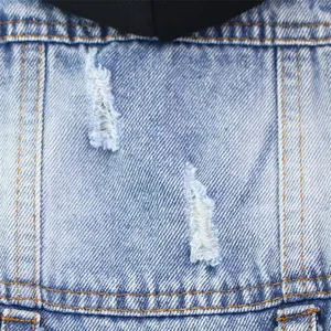 Detailed macro shot showing distressed holes and stitching on a denim hooded pet vest