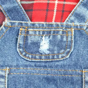 Macro detail of denim pet jumpsuit with frayed pocket and stylish red plaid lining