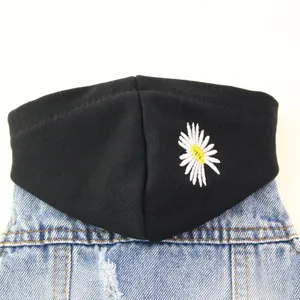 Close-up detail of a pet denim vest featuring a black hood with white daisy floral embroidery