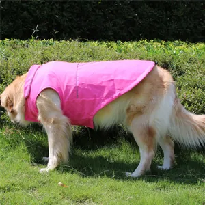 Vista lateral de un perro grande con una chaqueta rosa impermeable sobre el césped
