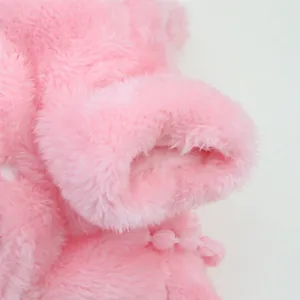 Macro detail of pink plush pet clothes showing soft fleece texture and pom-pom trim