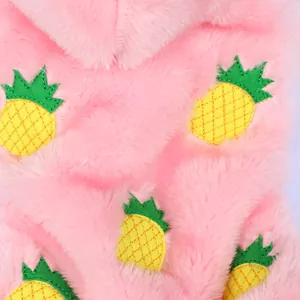 Macro detail of soft pink plush pet garment with yellow pineapple embroidery