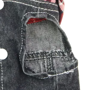 Detailed view of the durable stitching and red plaid lining on a denim dog vest