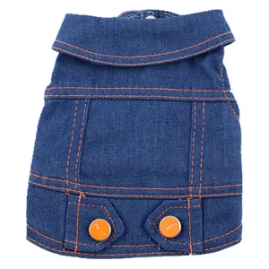 Gros plan d'un gilet en jean bleu pour chien avec coutures orange et boutons décoratifs.